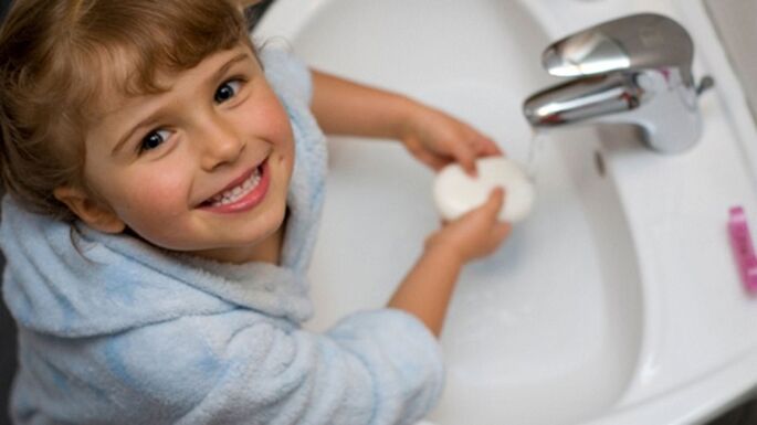 het kind wast zijn handen met zeep om wormen te voorkomen